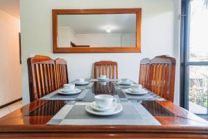 a dining room table with chairs and a mirror at Dois quartos com ar a 190 m de praia Paradisíaca in Guarapari