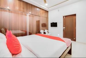 1 dormitorio con 1 cama blanca grande con almohadas rojas en Hotel RVN, en Nellore