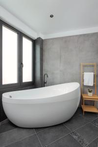 un bagno con grande vasca bianca di THE URBANIST •inner city residences• a Ioannina