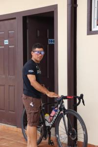 Un uomo che tiene una bicicletta davanti alla porta di Hotel Residencial Panamericano a David