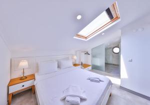 a bedroom with a white bed and a skylight at Hemera Suite in Kas