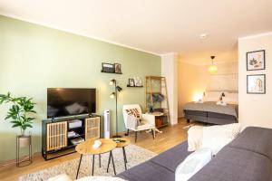 ein Wohnzimmer mit einem Sofa, einem TV und einem Bett in der Unterkunft FeWo Ahrperle-modernes Apartment-Balkon-Kurviertel in Bad Neuenahr-Ahrweiler