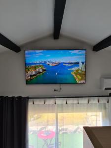 TV de pantalla plana en la pared en una habitación con ventana en Gîte spa la parenthèse en Sauve