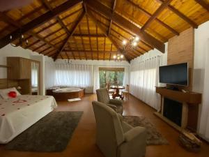 een grote woonkamer met een televisie en een tafel en stoelen bij Chalés Recanto das Montanhas in Monte Verde