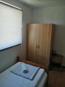 ニンにあるDanica apartmaniのベッドルーム1室(ベッド1台付)、木製キャビネットが備わります。