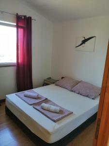 1 dormitorio con cama blanca y cortina roja en Danica apartmani en Nin