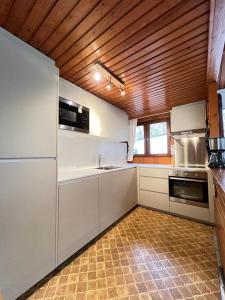 una cucina con elettrodomestici bianchi e soffitto in legno di Chalet 172 - La Boverie a Rendeux