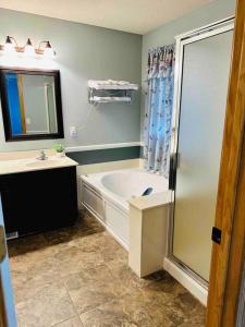 a bathroom with a bath tub and a sink at The Falmouth Villa with Peloton Bike in Shakopee