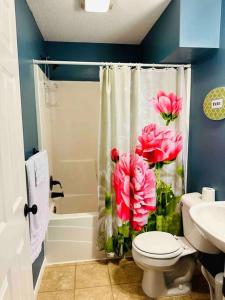 a bathroom with a shower curtain with pink flowers on it at The Falmouth Villa with Peloton Bike in Shakopee