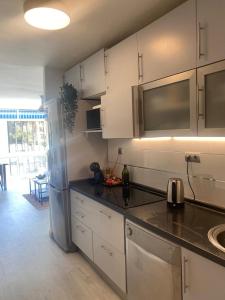 eine Küche mit weißen Schränken und einem Kühlschrank aus Edelstahl in der Unterkunft Sunny Seaview Apartment in Torremolinos