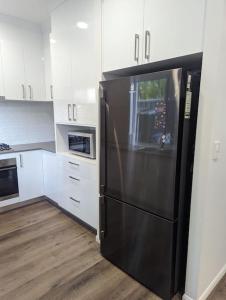 a black refrigerator in a kitchen with white cabinets at Entire House near Brisbane City 2Beds in Brisbane
