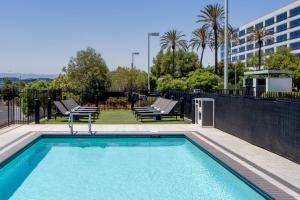 una piscina con 2 sillas y un edificio en Aloft Santa Clara - San Jose North, en San José