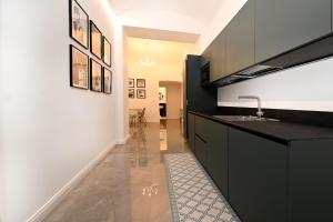 een keuken met zwarte kasten en een spoelbak bij VATICAN DESIGN APARTMENTS in Rome