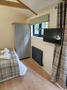a bedroom with a bed and a flat screen tv at Woodland Shephards Hut - 'Aristocrat' in Caernarfon
