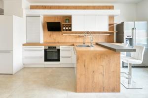 a kitchen with white cabinets and a wooden counter top at WeinlandMotel in Ebenthal