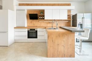 a kitchen with white cabinets and a wooden counter top at WeinlandMotel in Ebenthal +5 photos