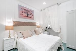 ein weißes Schlafzimmer mit einem weißen Bett und einem Baumgemälde an der Wand in der Unterkunft Glint House Roma in Rom