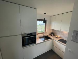 a kitchen with white cabinets and a sink and a window at Maison Coxyde in Koksijde