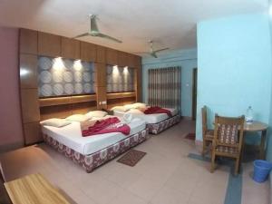 two beds in a room with a table and chairs at Saint Martin Resort in Cox's Bazar