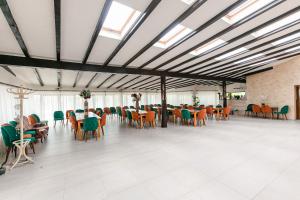 a large room with tables and chairs and windows at Pensiunea Casa de Vis in Bughea de Sus