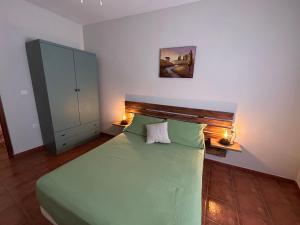 a bedroom with a green bed with two pillows at Casa Rural Cerezo in Torviscón