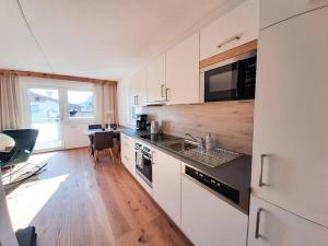 een keuken met witte kasten, een wastafel en een tafel bij Hornblick Suite *NEW* Stylish 1BR + Netflix in Kirchdorf in Tirol