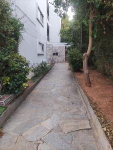a stone walkway in front of a white building at VOULIAGMENI RIVIERA center between Beach and Lake in Athens