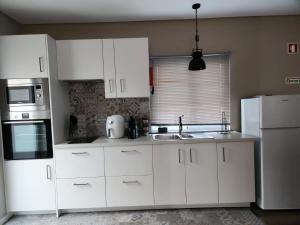 a kitchen with white cabinets and a white refrigerator at Rosegarden View in Velas