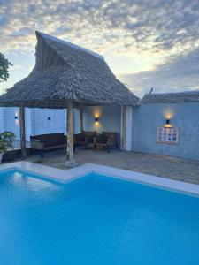 a swimming pool with a large umbrella and a house at Shany’s Villa 3bdrm with private swimming pool in Mombasa