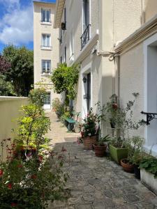une cour avec des plantes en pot et un bâtiment dans l'établissement Charmant studio proche RER B direction Paris, à Fontenay-aux-Roses