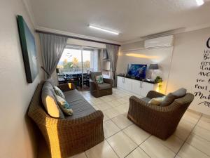 a living room with a couch and chairs and a television at 196 Laguna La Crete in Uvongo Beach +24 photos