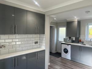 uma cozinha com armários cinzentos e uma máquina de lavar roupa em The Coral 24 Guest House MilBrook Southampton em Southampton