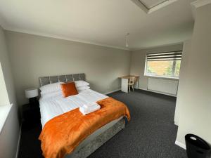 ein Schlafzimmer mit einem großen Bett mit einer orangefarbenen Decke in der Unterkunft The Coral 24 Guest House MilBrook Southampton in Southampton