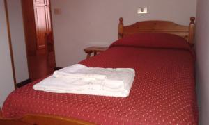 Una cama roja con toallas blancas. en Residence Cervinia Due - Maisonnette nr A7A04, en Breuil-Cervinia