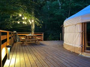 eine Holzterrasse mit einem Tisch und einem Zelt in der Unterkunft Aux Étangs de Jourgnac - Yourte in Jourgnac