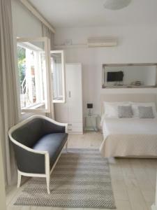 a white bedroom with a bed and a chair at Apartments Emi in Dubrovnik