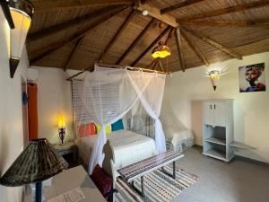 a bedroom with a bed and a wooden ceiling at Keur Papaye in Dinouar