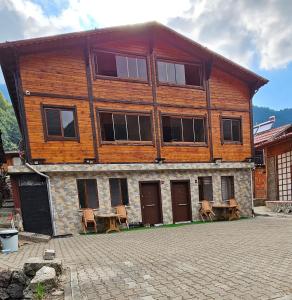 a large wooden building with chairs in front of it at Uzungöl Sakin Pansiyon in Uzungöl +51 photos