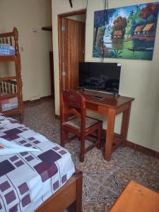 a bedroom with a desk and a bed and a bed and a television at HOTEL SOL Y LUNA in Iquitos