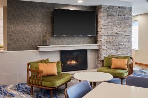 a living room with a fireplace and a tv at Fairfield Inn & Suites Burlington in Burlington