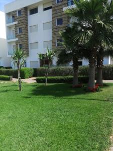 a building with palm trees in front of a yard at TAMARIs in Tamaris