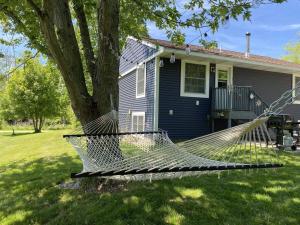 a hammock in front of a house with a tree at BlueHaven: Your Cozy Lakeside Retreat in Glenn