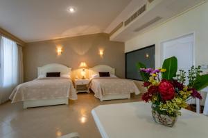 a hotel room with two beds and a vase of flowers at Excelaris Grand Resort Conventions & Spa in Tequesquitengo