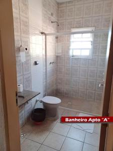 a bathroom with a toilet and a glass shower at Rial Hotel in Itanhaém