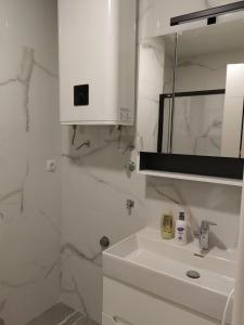 a white bathroom with a sink and a mirror at Apartman Herc in Trebinje