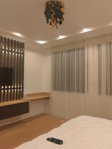 um quarto com uma cama, uma televisão e um controlo remoto em Apartman Herc em Trebinje
