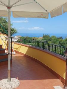 a balcony with an umbrella and the ocean in the background at CASA VACANZA DEL SOLE in Milo