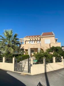 a house with a fence and a palm tree at Ceka Apartments in Ulcinj