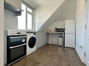 a kitchen with a stove and a washer and dryer at Stylish Modern, 1 Bed Flat, 15 Mins To Central London in Hendon