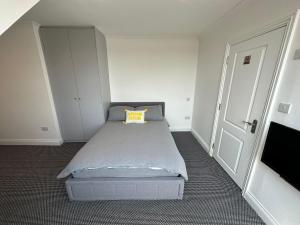 a bedroom with a bed with a yellow pillow on it at Stylish Modern, 1 Bed Flat, 15 Mins To Central London in Hendon